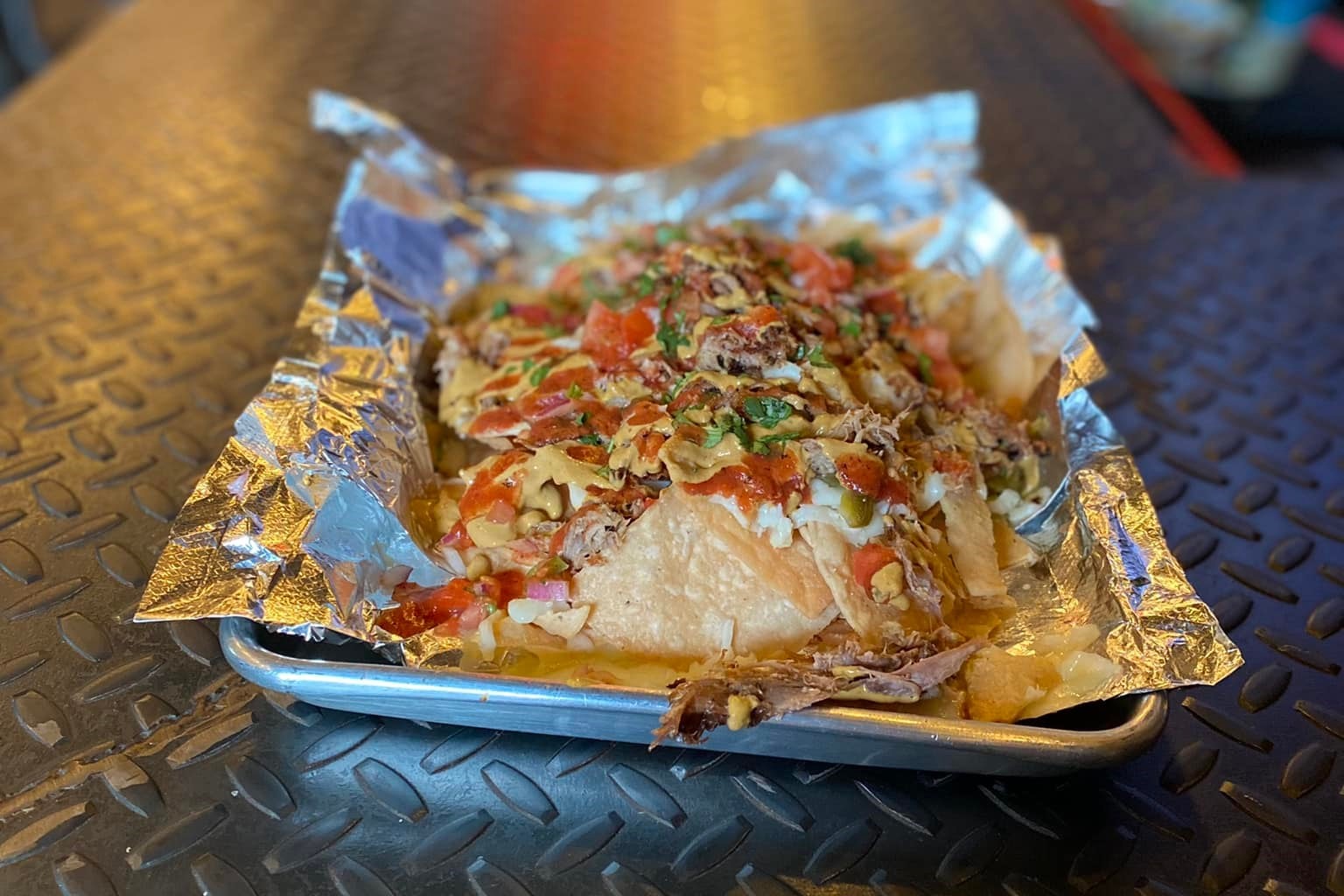 Borracho Saloon nachos plated on a silver tray on top of tin foil