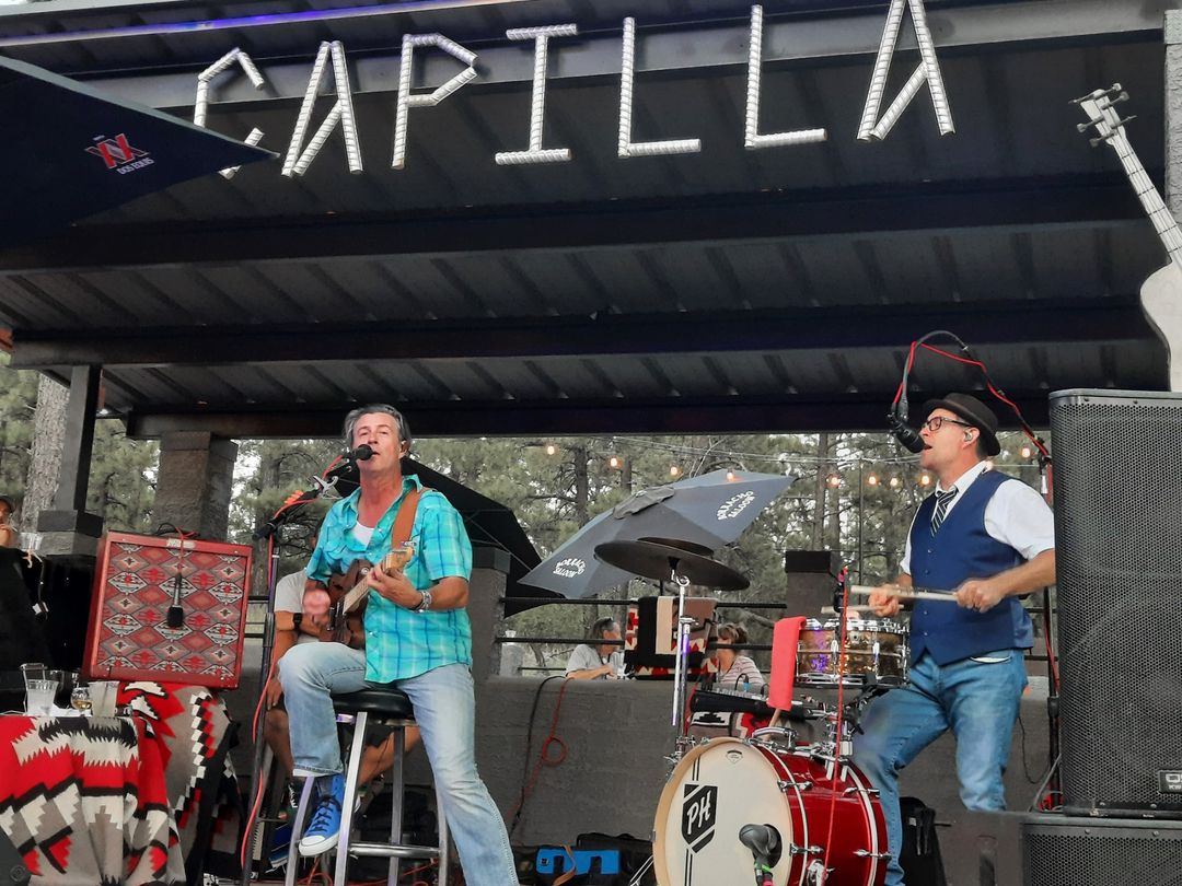 Man singing playing guitar and man singing playing the drums on the Borracho Saloon La Capilla stage