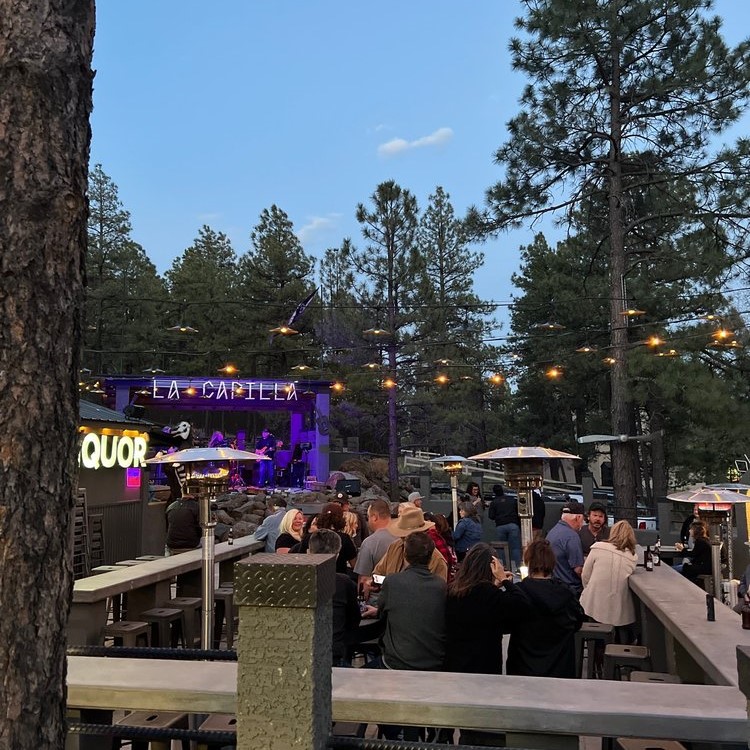 A nearly filled Borracho Saloon patio with customers enjoying food and drink with live music on the Borracho Saloon La Capilla stage going on in the background